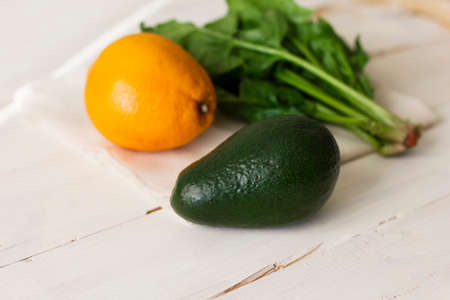 Bunch of fresh spinach, orange and avocado on a white wooden backgroundの写真素材