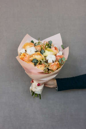 The delicate rustic floral bouquet in woman hands on grey backgroundの写真素材