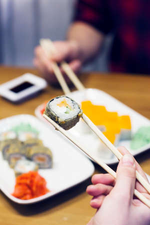 Sushi rolls on plate, friends taking rollsの写真素材