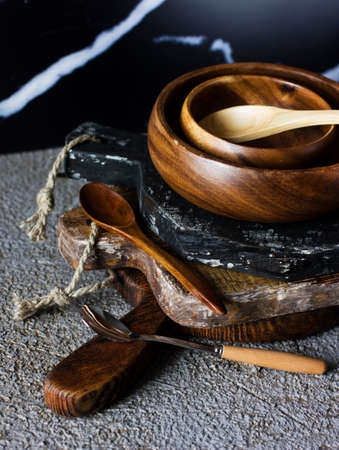 Wooden boards, bowl and spoons on grey concrete background. Props for food photographyの写真素材