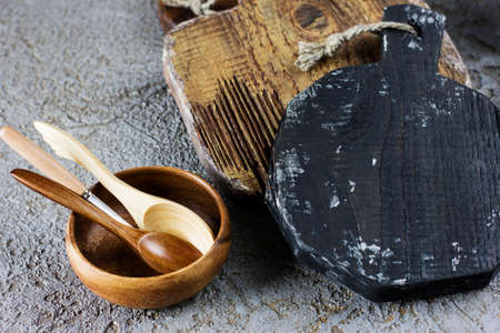 Wooden boards, spoons and bowl on grey concrete background. Props for food photographyの写真素材