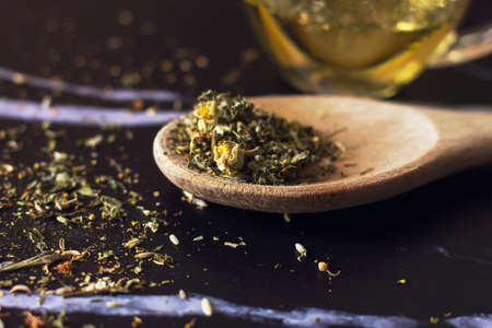 Herbal tea in a wooden spoon on a black marble backgroundの写真素材