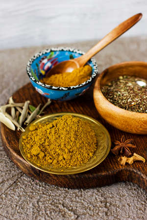 Different dry spices in bowls on a wooden Board on a concrete backgroundの写真素材
