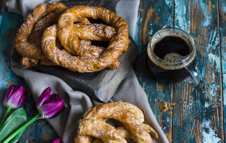 Fresh baked pretzels, flowers and coffee on shabby wooden blue backgroundの写真素材