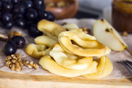 String Cheese, honey, grapes, pears and nuts on wooden board on kitchenの写真素材