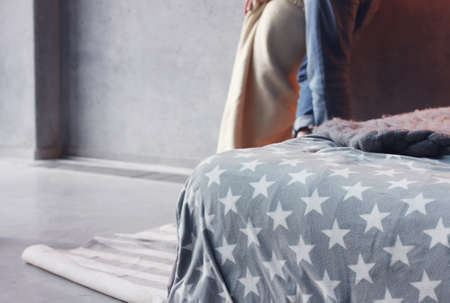 Loft style bedroom, bed with grey blanket and couple in the backgroundの写真素材