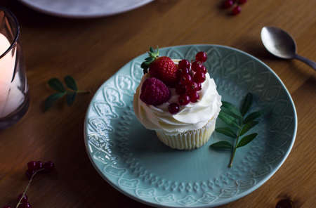 Homemade cupcake with vanilla cream, fresh berries in mint plate on festive table