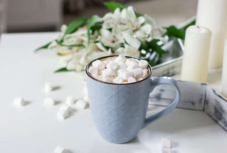 Blue mug with cocoa, coffee, marshmallows on white table with decorの写真素材