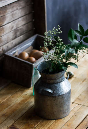 Rustic bouquet of herbs in aluminum cans, chicken eggs in box on the tableの写真素材