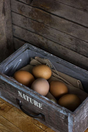 Brown chicken eggs in an old wooden box, home farm