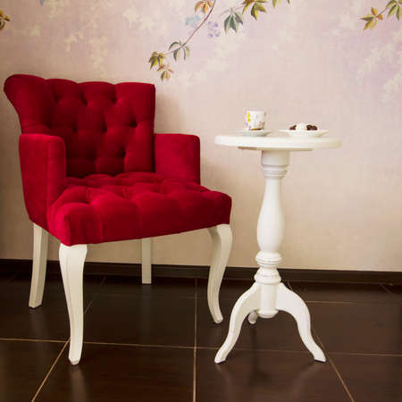 Red armchair and white round coffee table place to relax, interior detailsの写真素材