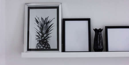 Posters with pineapple and clean frames on the shelf, modern interior in black and white, bannerの写真素材