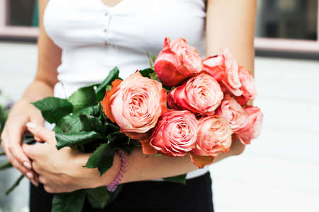 Young woman florist holding bouquet of pink roses at the streetの写真素材