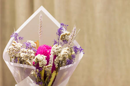 Bouquet of dried flowers spikelets in floral paper on beige backgroundの写真素材