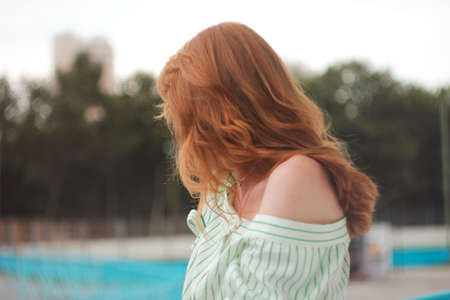 Red hair woman standing backwards outdoors, miss you conceptの写真素材