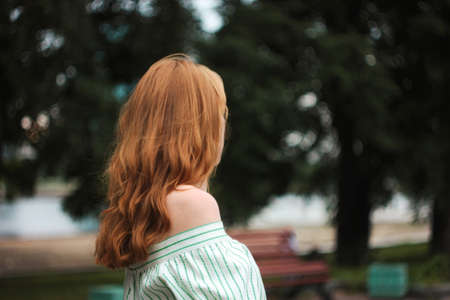Red hair woman standing backwards outdoors, miss you concept