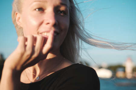 Lifestyle portrait of young blonde woman at sunset and windy, selective focus