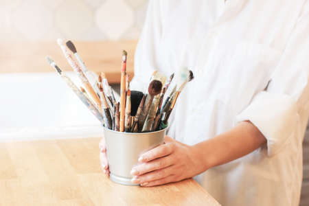 Different brushes in metal bucket with artist hands, selective focusの写真素材
