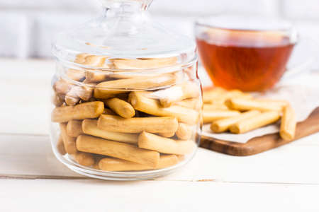 Puff pastry sticks in glass jar with cup of tea