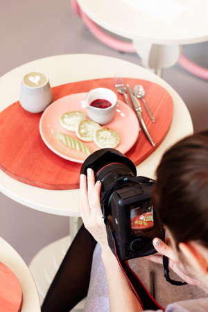 Young woman food photographer shoots Breakfast in cafe, workflowの写真素材