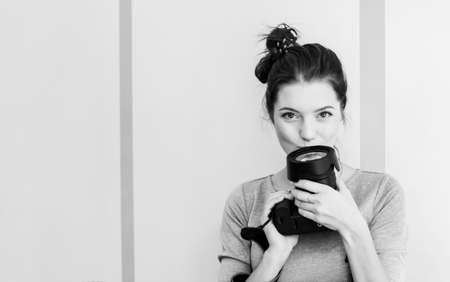 Pretty girl photographer kisses her camera and smiles, black and white photoの写真素材