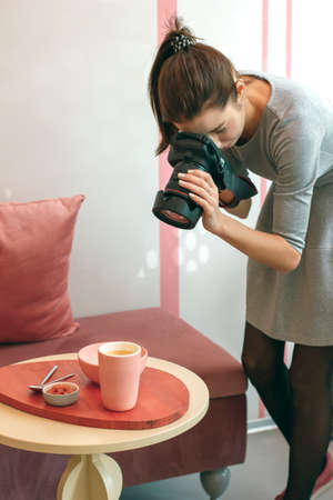 Young woman food photographer blogger shoots Breakfast in cafe, working process