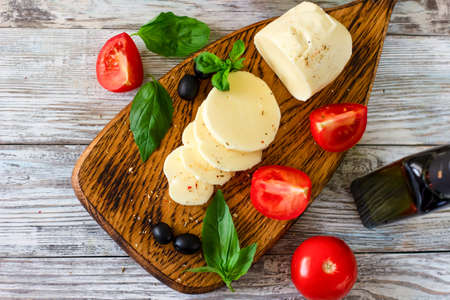 Mozzarella cheese with tomatoes and Basil on wooden background, top viewの写真素材