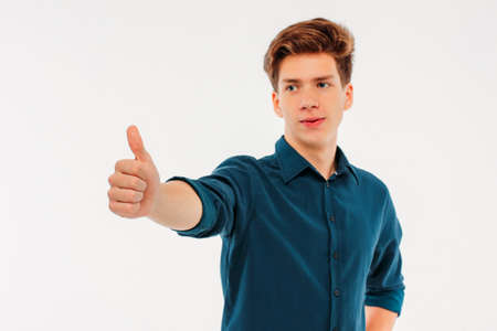 Attractive smiling boy 18 years old student showing thumbs up on white background