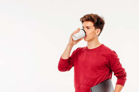 Smiling young man student with coffee to go and laptop on white backgroundの写真素材