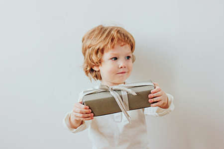 Pretty little boy holding gift box, minimalism styleの写真素材