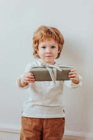 Pretty little boy holding gift box, minimalism styleの写真素材