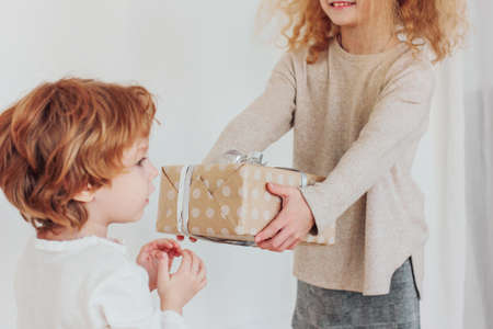 Sister gives gift to younger brotherの写真素材