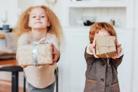 Little brother and the sister give gifts. Focus on boxes, toned photoの写真素材