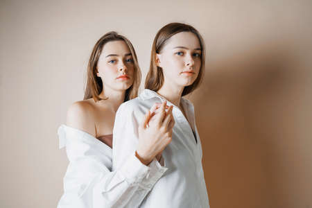 Fashion models two sisters twins beautiful nude girls looking at the camera isolated on beige backgroundの写真素材