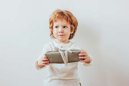 Pretty little boy holding gift box, minimalism style