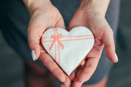 Heart white glazed gingerbread in woman hands, Valentine's day conceptの写真素材