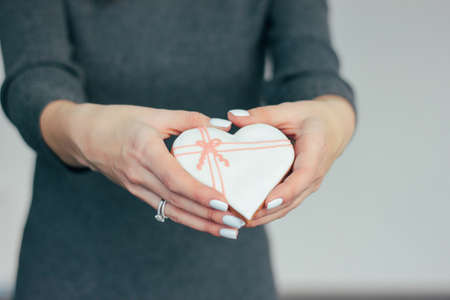 Heart white glazed gingerbread in woman hands, Valentine's day conceptの写真素材