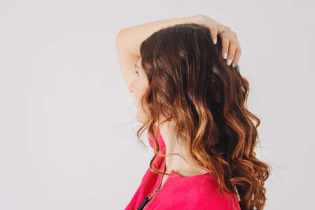 Beautiful charming brunette girl in bright pink dress looking up on gray background isolatedの写真素材