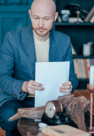 The bald bearded man in blue jacket suit holding sheets of paper in his handsの写真素材