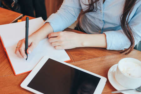 Beautiful charming brunette girl with tablet at table in cafe, student, freelancerの写真素材