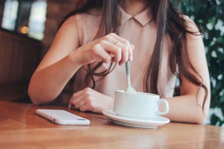 Crop photo of young woman girl with cup of coffee or tea, sitting at cafeの写真素材