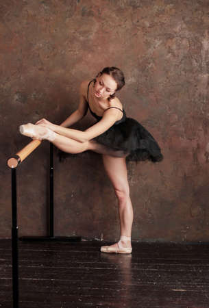 Ballet dancer ballerina in beautiful black dress tutu skirt is posing in loft studioの写真素材