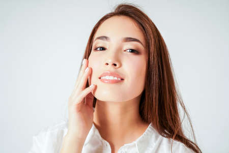 Beauty portrait of smiling sensual asian young woman with clean fresh skin in white shirt isolated