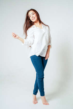 Beauty fashion full length portrait of smiling sensual asian young woman with dark long hair in white shirt on white backgroundの写真素材