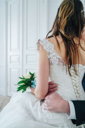 Just married couple with bouquet of white roses in studio, wedding details close upの写真素材