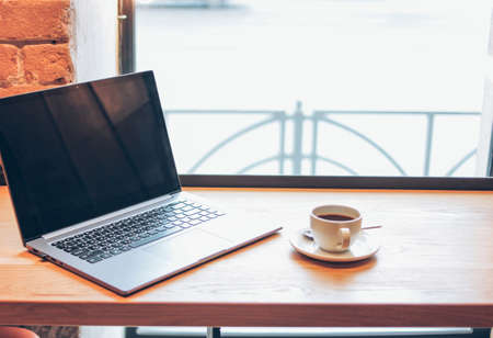 Open laptop and a Cup of coffee on the table in the cafe, freelance conceptの写真素材