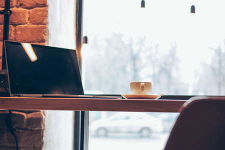 Open laptop and a Cup of coffee on the table in the cafe, freelance conceptの写真素材