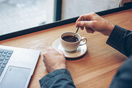 Open laptop and men hands with a Cup of coffee on table in cafeの写真素材