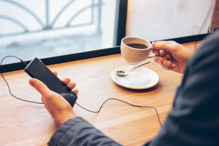 The man using mobile phone with headphones at cafe