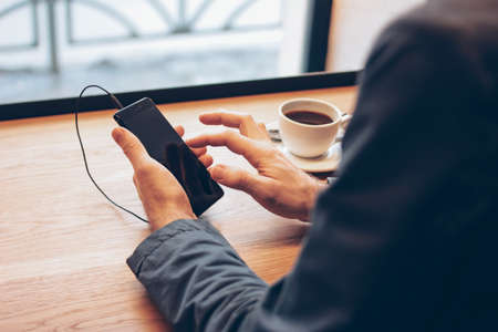 Man using mobile phone with headphones at cafe